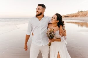 Esposos disfrutando de su matrimonio en la playa y sonriendo