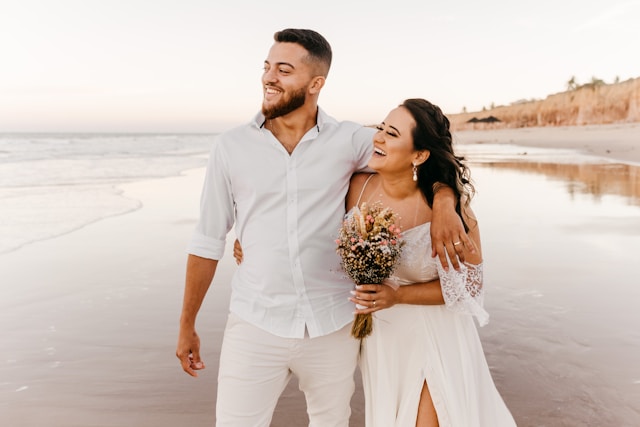 Esposos disfrutando de su matrimonio en la playa y sonriendo
