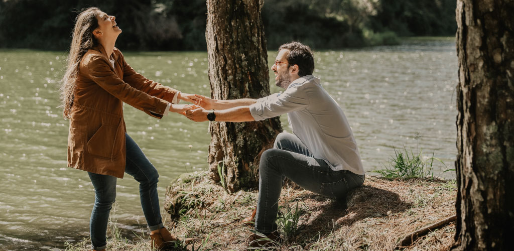 Pareja de enamorados en el campo, ella levantando al hombre de forma divertida al hombre.