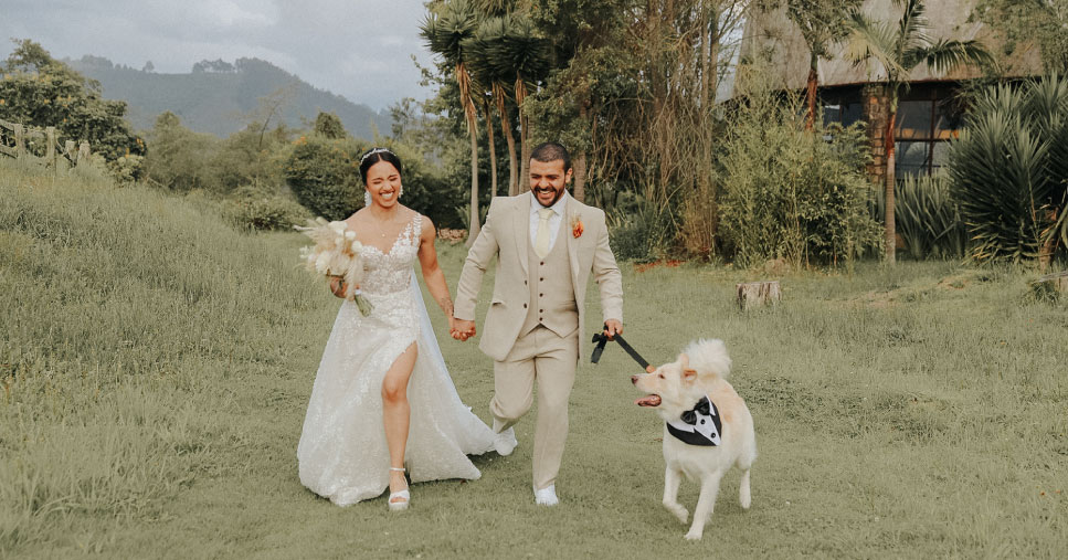 Pareja de esposos corriendo en el campo con su perro