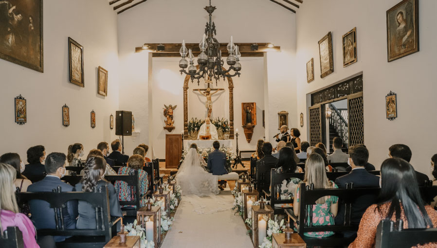 Pareja frente a un altar casándose en una iglesia católica junto a toda su familia