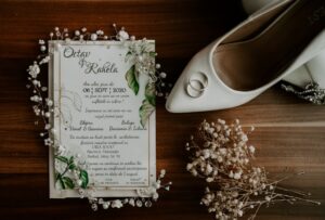 Invitación de matrimonio decorado con flores, zapato de la novia y argollas.