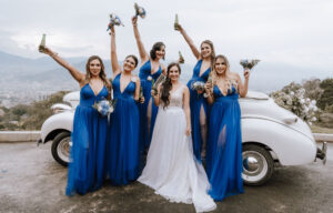 Novia celebrando su boda con las damos de honor vestidas con un vestido largo de color azul