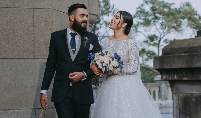 Novia con ramo de flores de colores con su esposo al lado