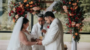 Novios intercambian votos bajo un arco floral en una boda católica