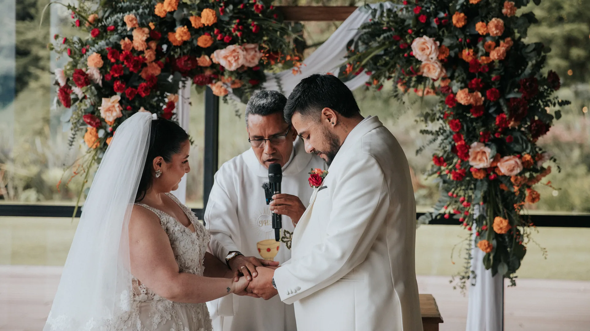 Novios intercambian votos bajo un arco floral en una boda católica