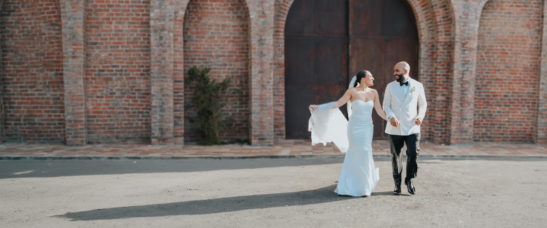 Novios caminan frente a una iglesia de ladrillo en una boda de destino en Colombia