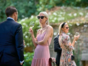 Invitados con vestido rosado y traje formal brindan en una boda de jardín